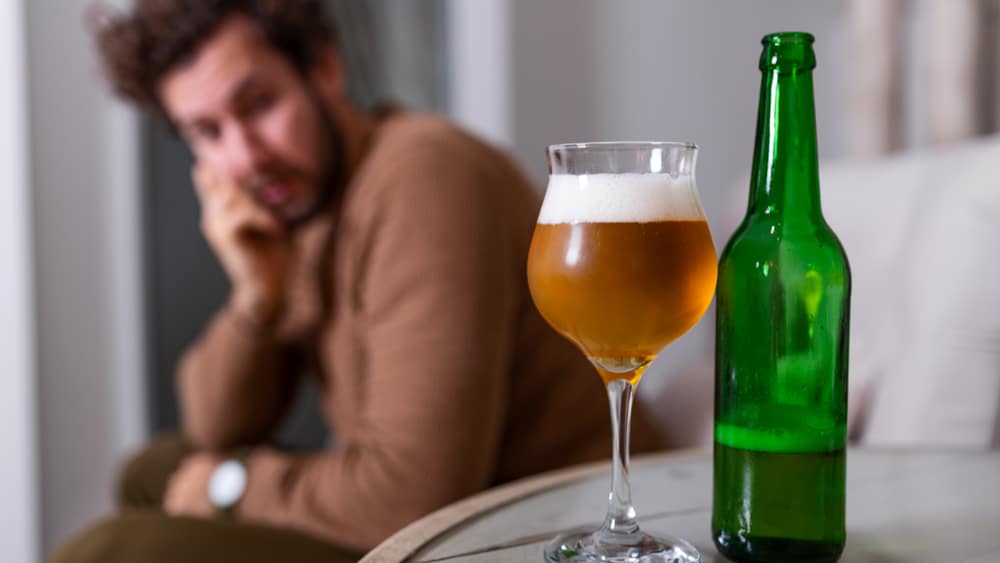 The 7 Types of Alcoholics North Jersey Recovery Center – 1788664802 The 7 Types of Alcoholics North Jersey Recovery Center - A depressed young male sits on a couch staring at a beer bottle and a glass filled with beer as he contemplates his alcohol use and if he fits into the different types of alcoholics or not.