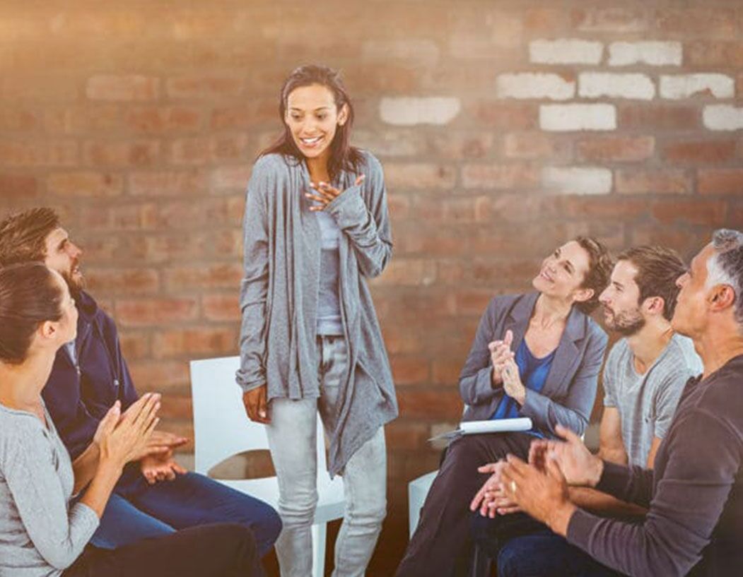 A woman speaking to an AA Group - twelve-step program outdated