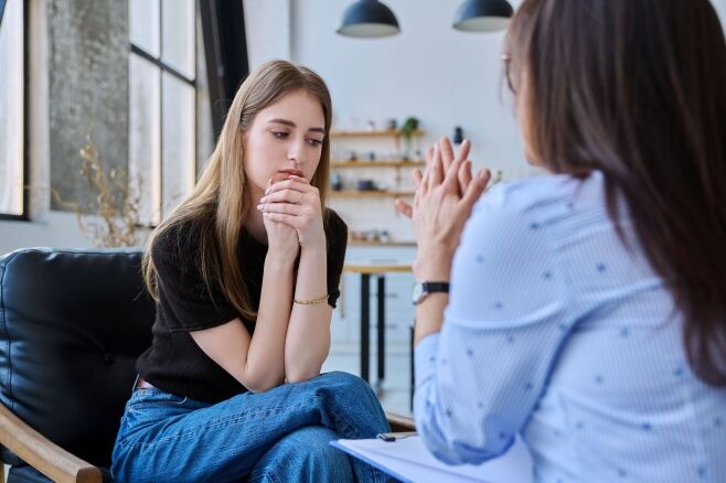 Young woman talking to social worker, home visit of psychological counselor